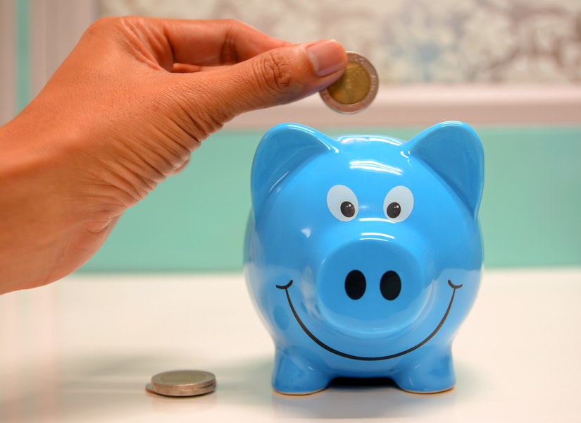 Hand putting money in a piggy bank