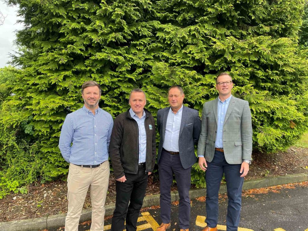 4 men standing side by side in front of a tree